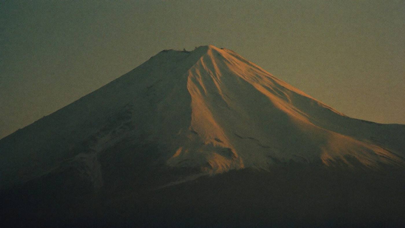 Cinematic view of a lone skier crossing a snowy Andean volcano at dusk