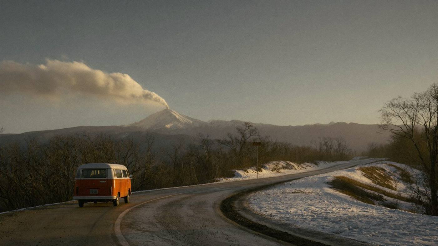 Cinematic orange camper van on a snow-dusted Andes road at golden hour