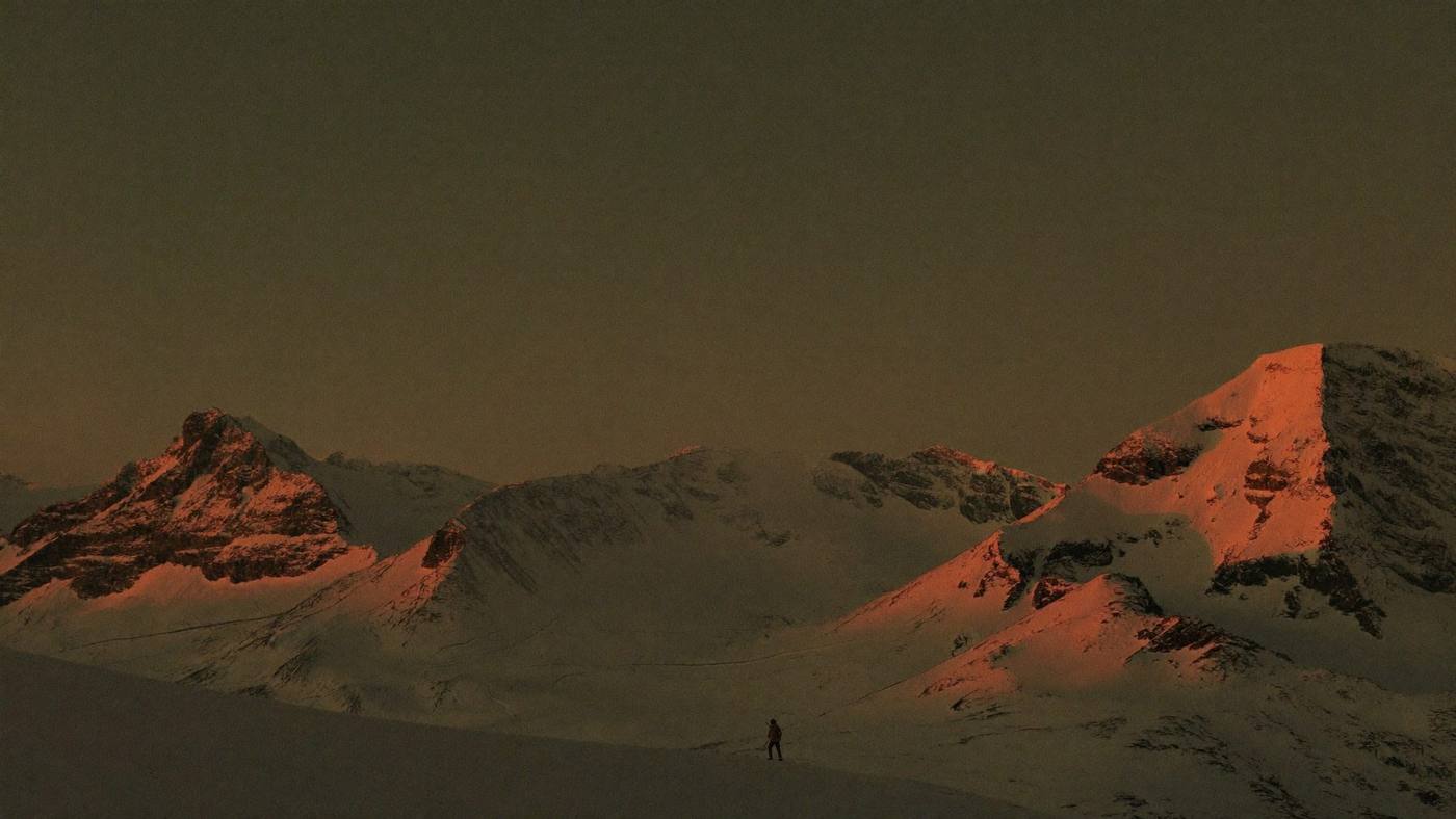 Cinematic view of a lone expedition traveller crossing the snowy Andes at sunset
